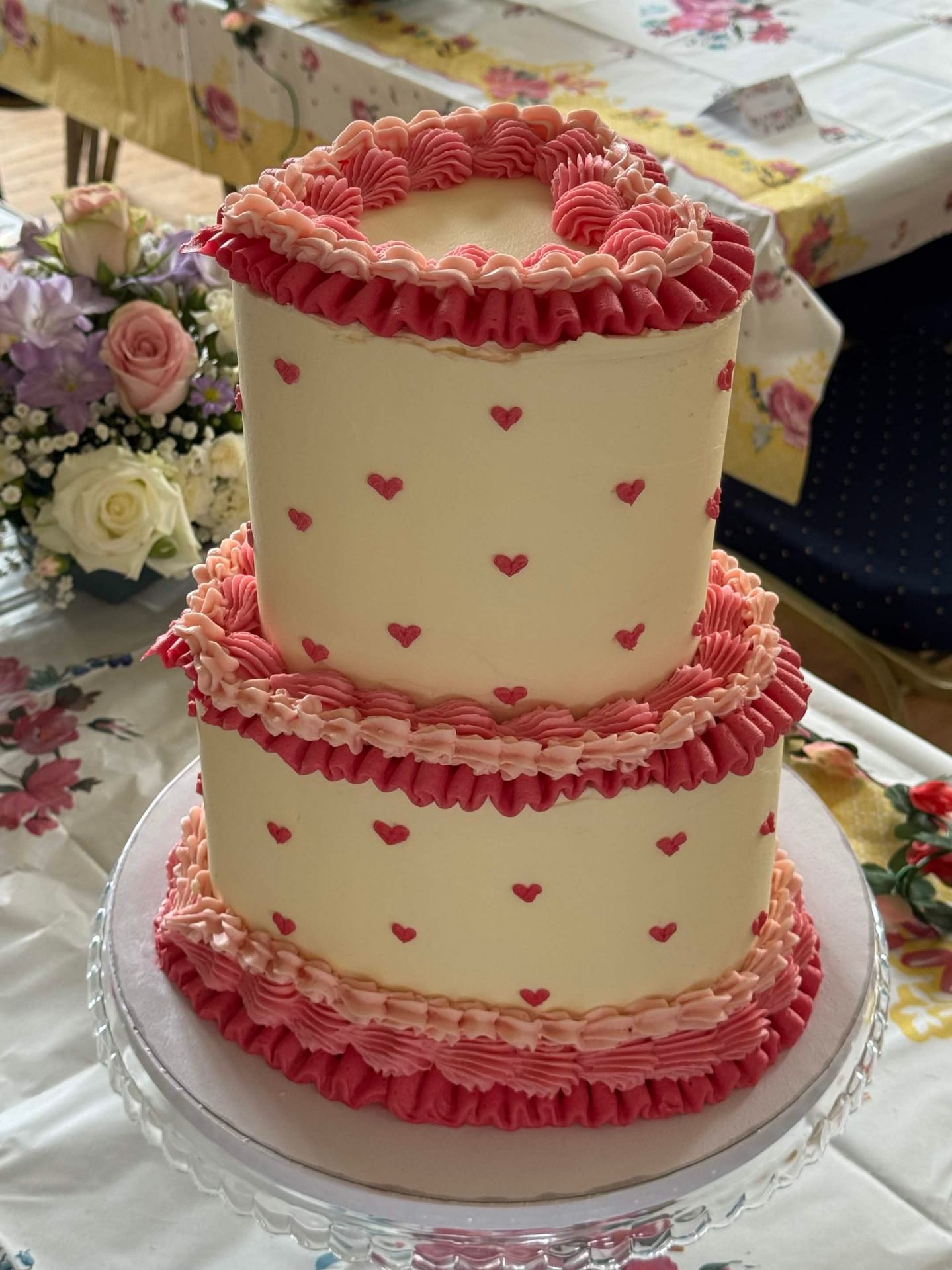 Two-tier ivory buttercream cake with piped hearts and ruffled trim