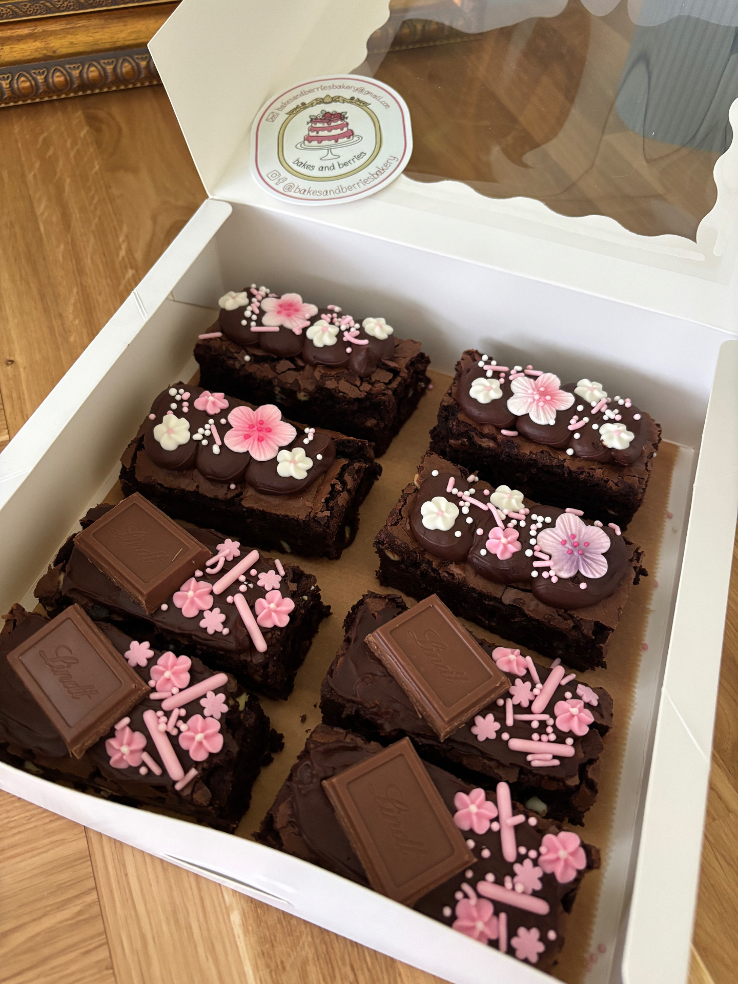 Box of chocolate brownies topped with pink blossoms, sprinkles and Lindt chocolate squares